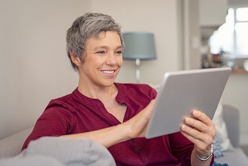 A happy mature woman sitting in a lounge using a tablet device